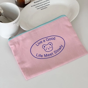 Close-up of pink canvas drawstring bag with cute bear print and light blue zipper detail