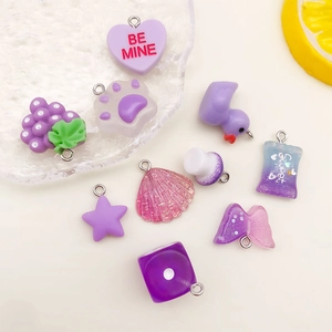 Flat lay of purple resin charms including hearts, stars, and paws for DIY jewelry making