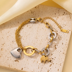Detalle de pulsera de acero oro y plata con dijes de corazón y elefante en piedra