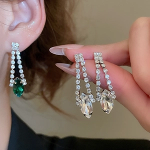 Close-up of tassel earrings featuring emerald green drops and sparkling crystals