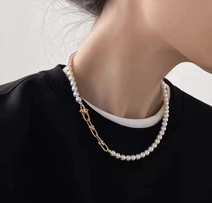 Eleganter goldener U-Verschluss an einer weißen Perlenkette am Hals eines Models