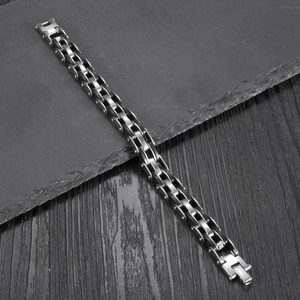 Men's silver stainless steel motorcycle chain bracelet on dark stone and wood background
