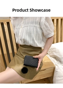 Detail of black quilted short wallet for women with decorative fur pompom charm