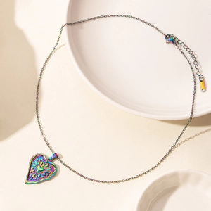 Close-up of rainbow heart pendant with embossed floral patterns and 18k gold plating