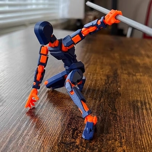 3D-gedruckte Dummy 13 Actionfigur in Blau und Orange posiert auf einem Holztisch