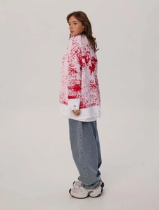 Detailed view of oversized distressed knit sweater featuring tattered cuffs and hem design
