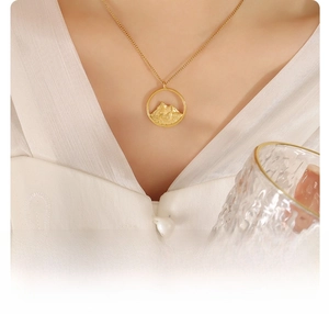 Detail of 18k gold plated titanium steel necklace with mountain relief pendant
