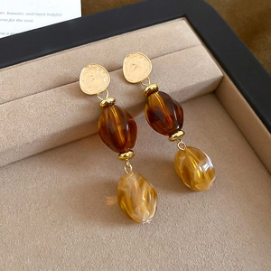 Detailed view of vintage amber acrylic earrings on a beige velvet display tray