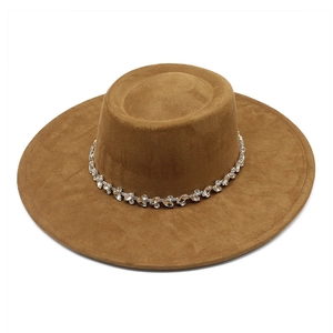 Détail d'un chapeau plat marron en faux daim avec une chaîne décorative en strass