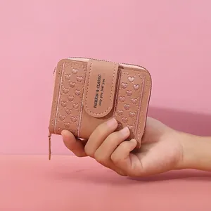 Pink short wallet for women with heart embroidery and zip closure in hand view