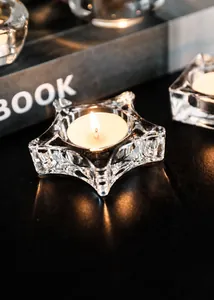 Macro detail of star-shaped clear glass candle holder with lit tea light candle