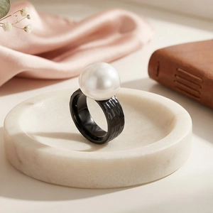 Detail shot of a minimalist hammered black metal ring featuring a large white pearl