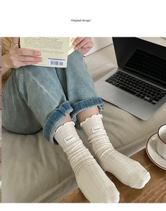 Detail of cream rib-knit mid-calf socks with ruffle trim and Sukinaini cloth label