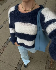 Close-up of soft knit blue and white striped sweater paired with jeans on the street
