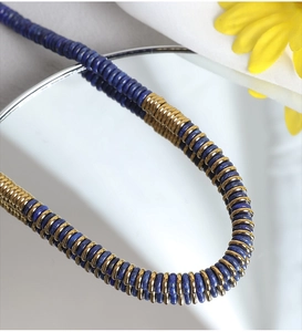 Macro shot of natural lapis lazuli beads with gold disc spacers on white texture