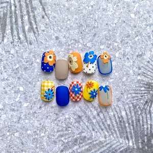 Floral embossed nail art stickers with blue and orange grid patterns on terrazzo backdrop