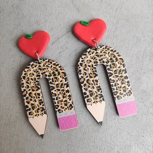 Detailed view of handmade teacher earrings featuring red apple studs and leopard rainbow pencils