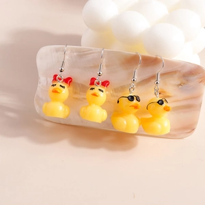 Cute yellow duck earrings with red bows and black sunglasses hanging on jewelry stand