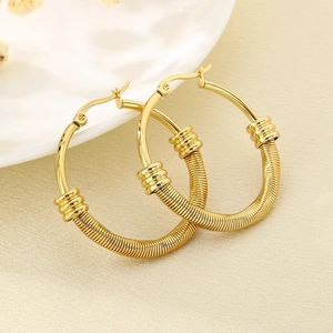 Détails de boucles d'oreilles créoles dorées avec fil enroulé et accents décoratifs
