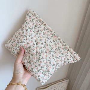Détail d'une trousse de maquillage matelassée à fleurs roses et étiquette en tissu doux