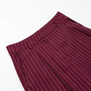 Detail of burgundy pinstripe trousers showing waist loops and pockets on suit fabric