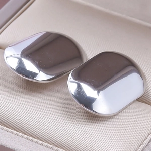 Macro detail of polished stainless steel silver hoop earrings with geometric design