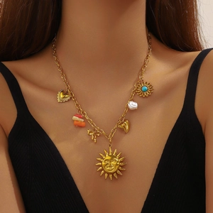 Gold-plated vintage necklace with sun face, heart, and pearl charms worn by a model