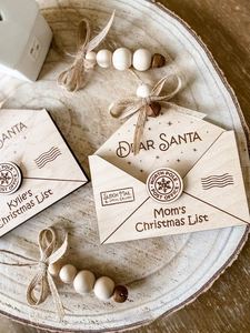 Macro shot of wooden Santa envelope ornament with twine, rustic beads and a small bronze bell