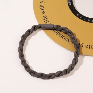 Detailed view of dark grey braided hair tie with a matte buckle on light background