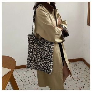 Detailed view of leopard print canvas tote bag carried by a model in a minimal indoor setting