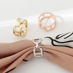 Three metal D-shaped scarf buckles in gold, silver, and rose gold on a striped silk scarf