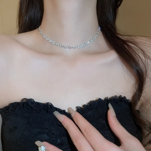 Close-up of elegant silver fringe necklace with zircon stones on model's neckline