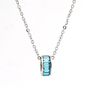 Detailed macro view of a silver necklace featuring a cylindrical pendant with blue stones