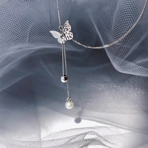 Macro view of silver butterfly pendant necklace featuring a lustrous round pearl drop