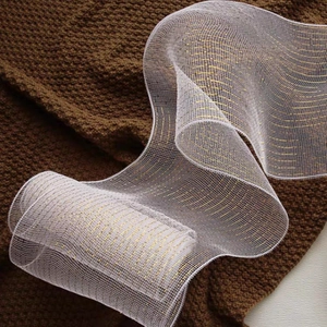 Macro detail of white Christmas mesh ribbon with golden metallic wire and stripe patterns