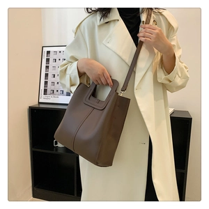 Vista dettagliata della borsa tote marrone caffè abbinata a un trench beige chic
