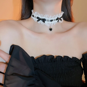 Detail of white lace choker with black fabric bow and black heart pendant on neck