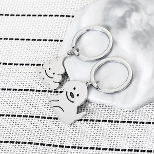 Close-up of a silver dog and poop emoji keychain set on a marble coaster