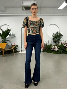 Dettaglio di jeans a zampa a vita alta con top a fiori con maniche a sbuffo e scollo quadrato