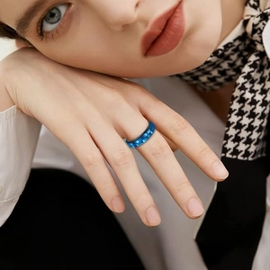 Close-up of a blue rotating gear ring on a finger with a houndstooth scarf detail