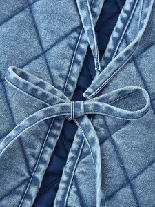 Close-up of diamond quilted denim fabric detail featuring a decorative bow tie design