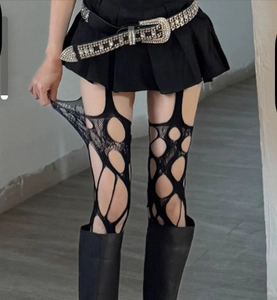 Detail of black punk style fishnet stockings with irregular distressed holes and tears