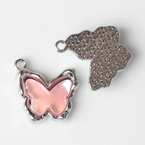 Detail showing pink resin butterfly pendant with silver metal frame and textured back