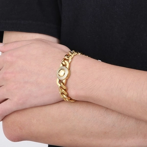 Close-up of a gold Cuban chain bracelet with a sparkling crystal-set round center on wrist