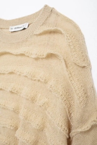 Detail of layered ruffle texture on beige mohair knit sweater showing delicate fuzzy fabric