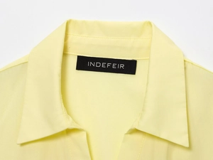 Detail of a light yellow poplin shirt collar with a classic lapel and black woven label