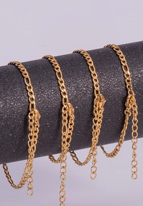 Detail of gold Figaro chain bracelet with shell charm and adjustable lobster clasp closure