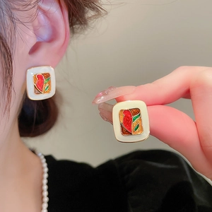 Detail of square vintage-style earrings with white enamel and colorful bird flower motifs