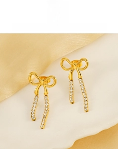Detail of gold bow earrings with crystal tassels on a decorative ceramic plate