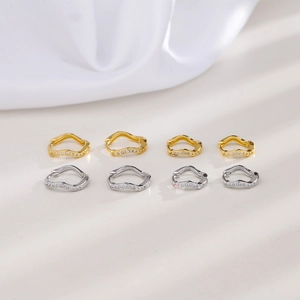 Close-up of gold and silver wave-shaped hoop earrings with micro-set zircon stones